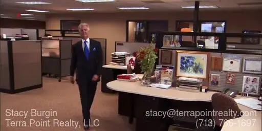 David Knox in a balck suit with white shirt and blue tie walking in an office talking about real estate