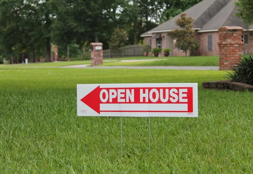 Open House sign with red arrow and white letters.  Has large yard with green grass