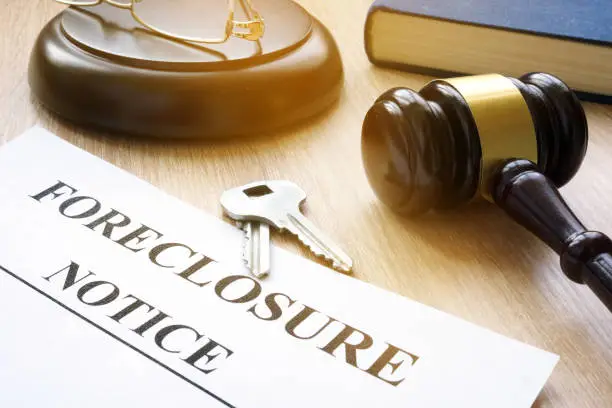 Foreclosure notice and house keys on a table, the paperwork side of buying a foreclosure in Texas